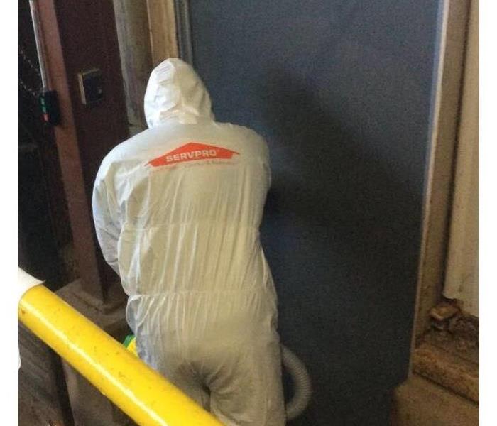 SERVPRO technician fogging door of a facility in full PPE
